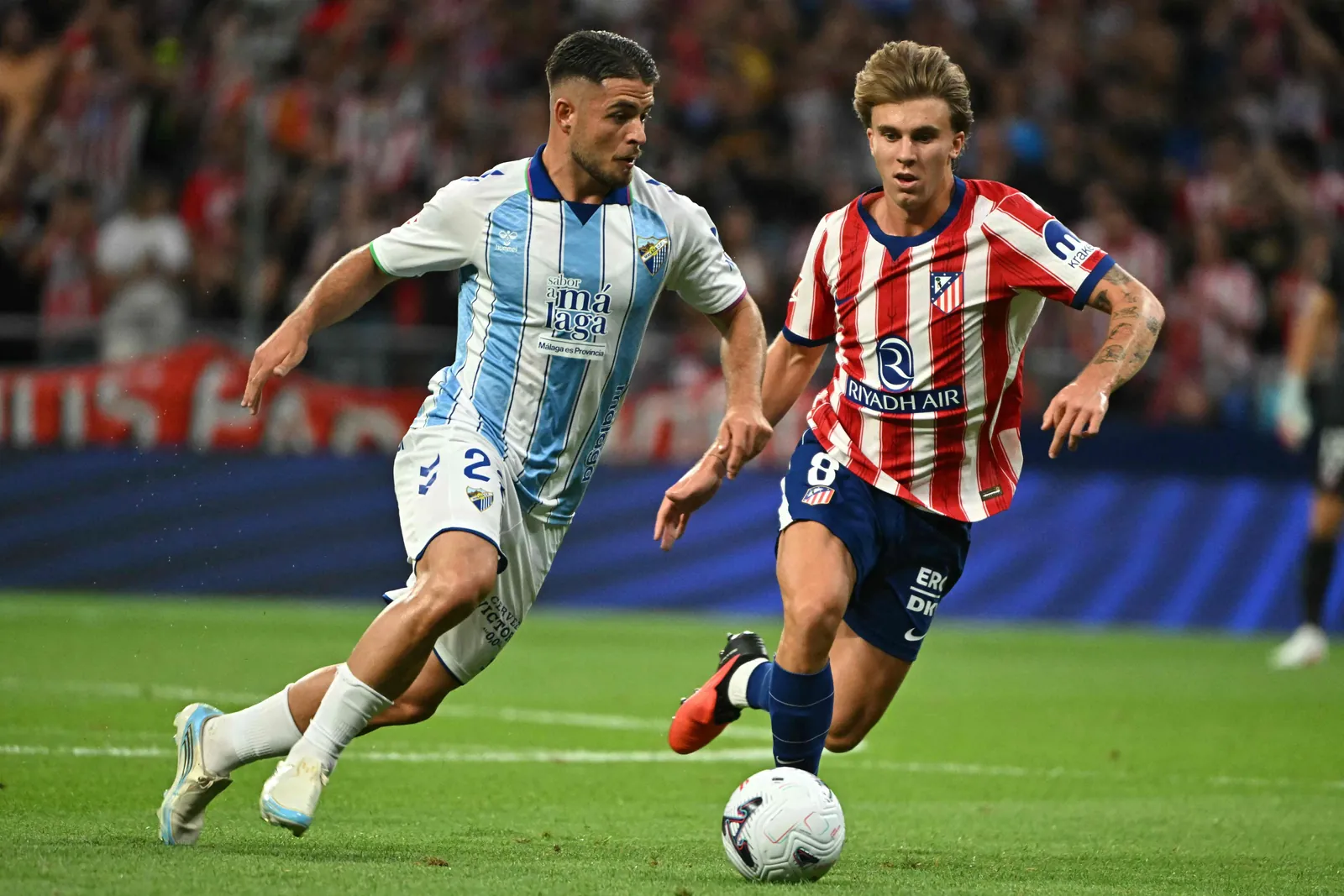 Spanish midfielder #22 Dani Lorenzo runs with the ball challenged by Atletico Madrid's Spanish midfielder #08 Pablo Barrios (R)